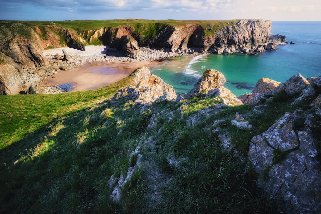 Golden sand, turquoise water and rocky cliffs at Bullslaughter Bay in Wales_The best UK holiday destinations for families