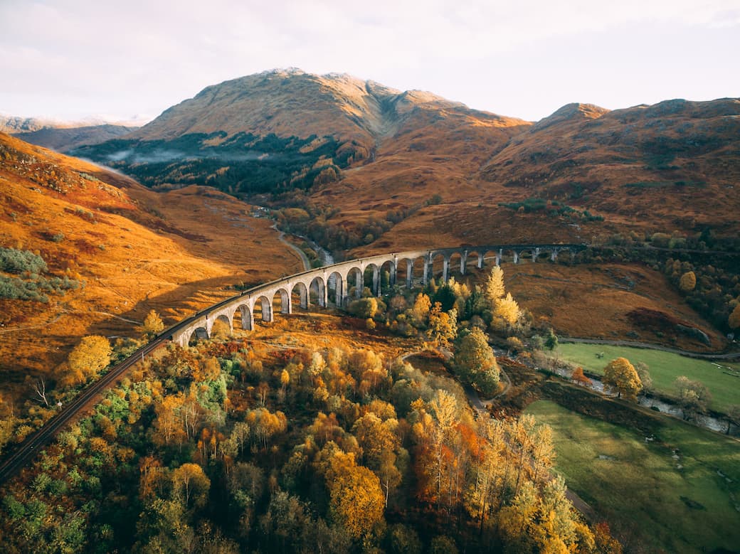 Gold and green hills and mountains crossed by The Glenfinnan Viaduct in Scotland_The best UK holiday destinations for families