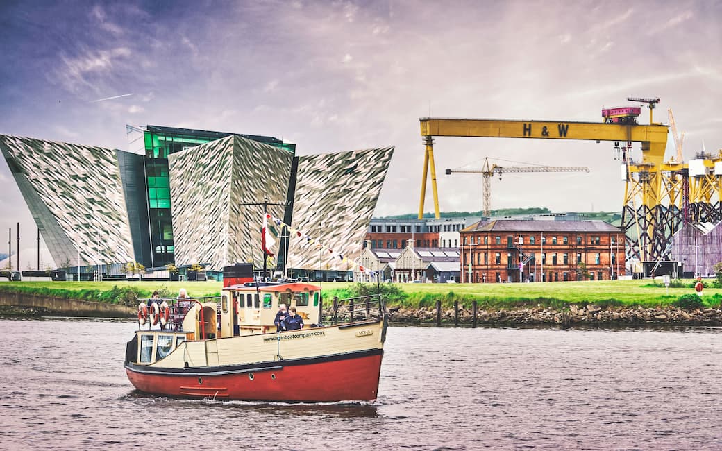Red fishing trawler on the water in front of the Titanic Belfast_The best UK holiday destinations for families