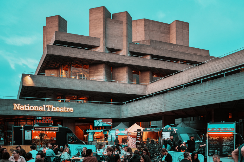 Modern concrete building with people and food stalls - The National Theatre in London is one of the best things to do on a rainy day in London