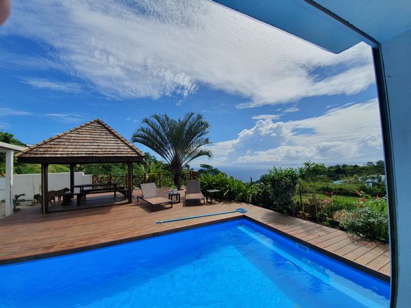 Maison moderne située dans les hauteurs de Tahiti avec vue mer et montagne.